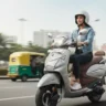 Hero Pleasure Plus electric scooter being ridden on a city road.