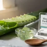 Fresh aloe vera leaf cut open and extracted gel in a glass bowl arranged on a stylish desk representing natural hair care ingredients.
