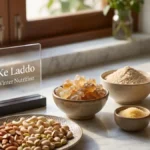 Edible gum crystals, wheat flour, ghee, and chopped nuts arranged on a stylish desk representing laddu ingredients.