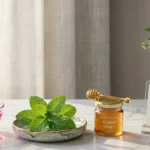 Fresh mint leaves and rose water bowl arranged on a stylish desk representing tan removal pack ingredients.
