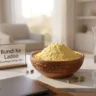 Sifted gram flour, sugar, and whole cardamoms arranged on a stylish desk representing homemade bundi ke ladoo ingredients.