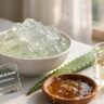 Aloe vera gel, honey, and coconut oil arranged on a stylish desk representing homemade hair spa cream ingredients.